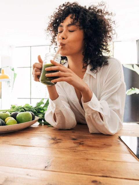 Woman drinking green smoothie through a straw