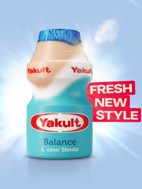 Yakult Balance bottle on a blue background with sunlight behind it and Fresh New Style written in a red ribbon