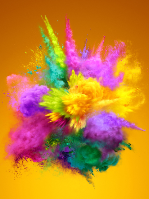 An explosion of colourful powders on an orange background