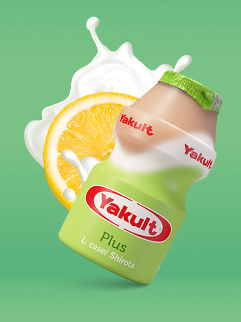 Geneigtes Yakult Plus Fläschchen mit einer Zitronenscheibe dahinter.