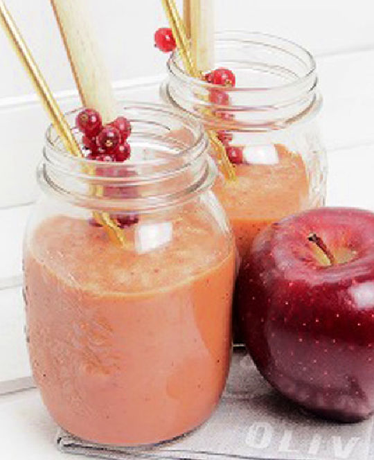 An orange smoothie in glass jars with gold straw