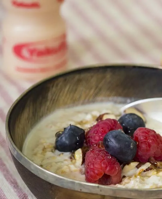 Havermoutmuesli , blauwe bessen, frambozen met een flesje Yakult Original.