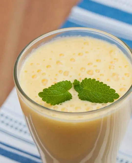 Mango-lassi in een glas met muntje met Yakult.