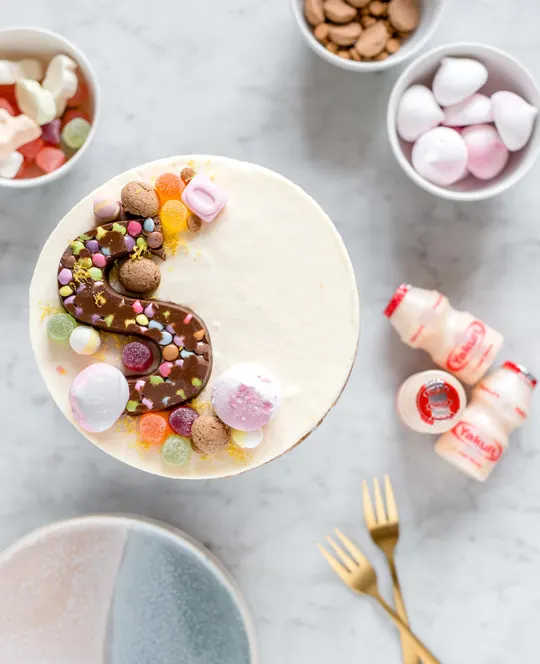 Sinterklaastaart versierd met lekkers, een chocolade S met de drie flesjes Yakult Original en lekkers eromheen.