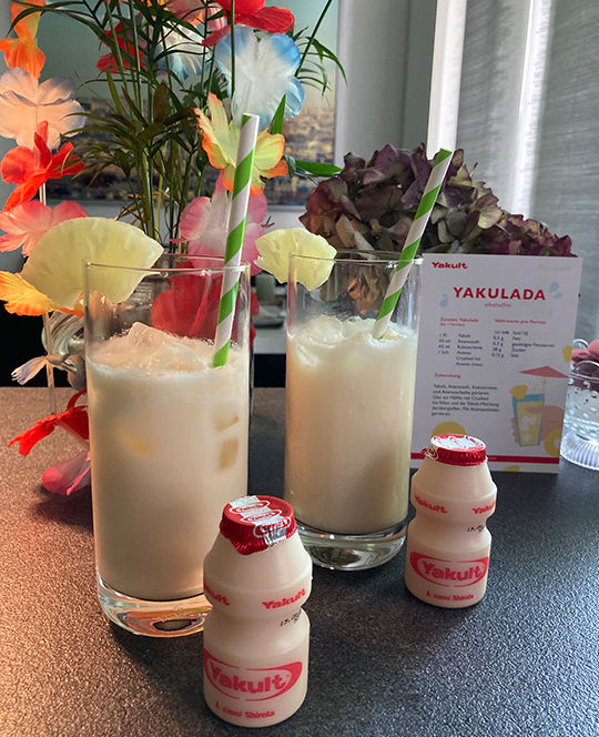 2 frisch gemixte Yakuladas in einem schönen Glas mit Strohhalm und 2 Yakult Original-Fläschchen.