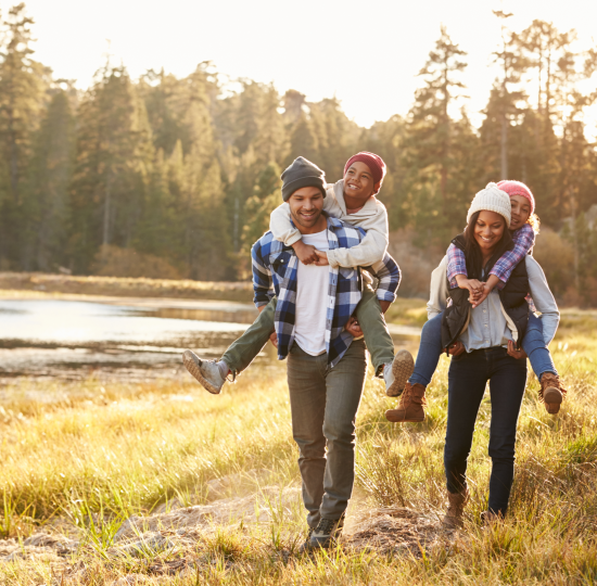 Parents giving children a piggyback in nature