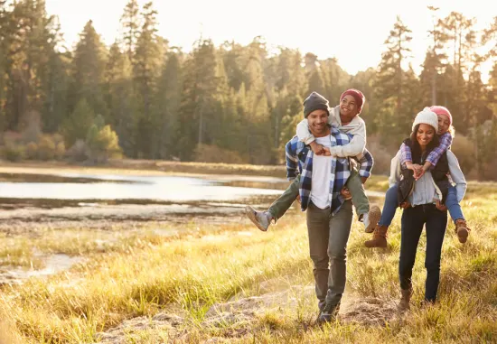 Man, vrouw met kinderen op de rug in de natuur.