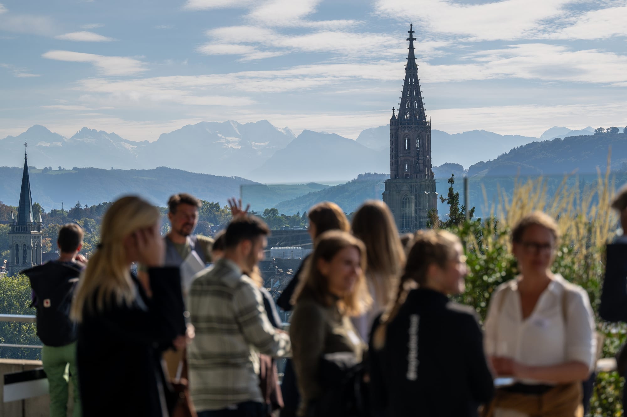 Panoramaaussicht Berner Alpen mit diskutierenden Menschen im Vordergrund