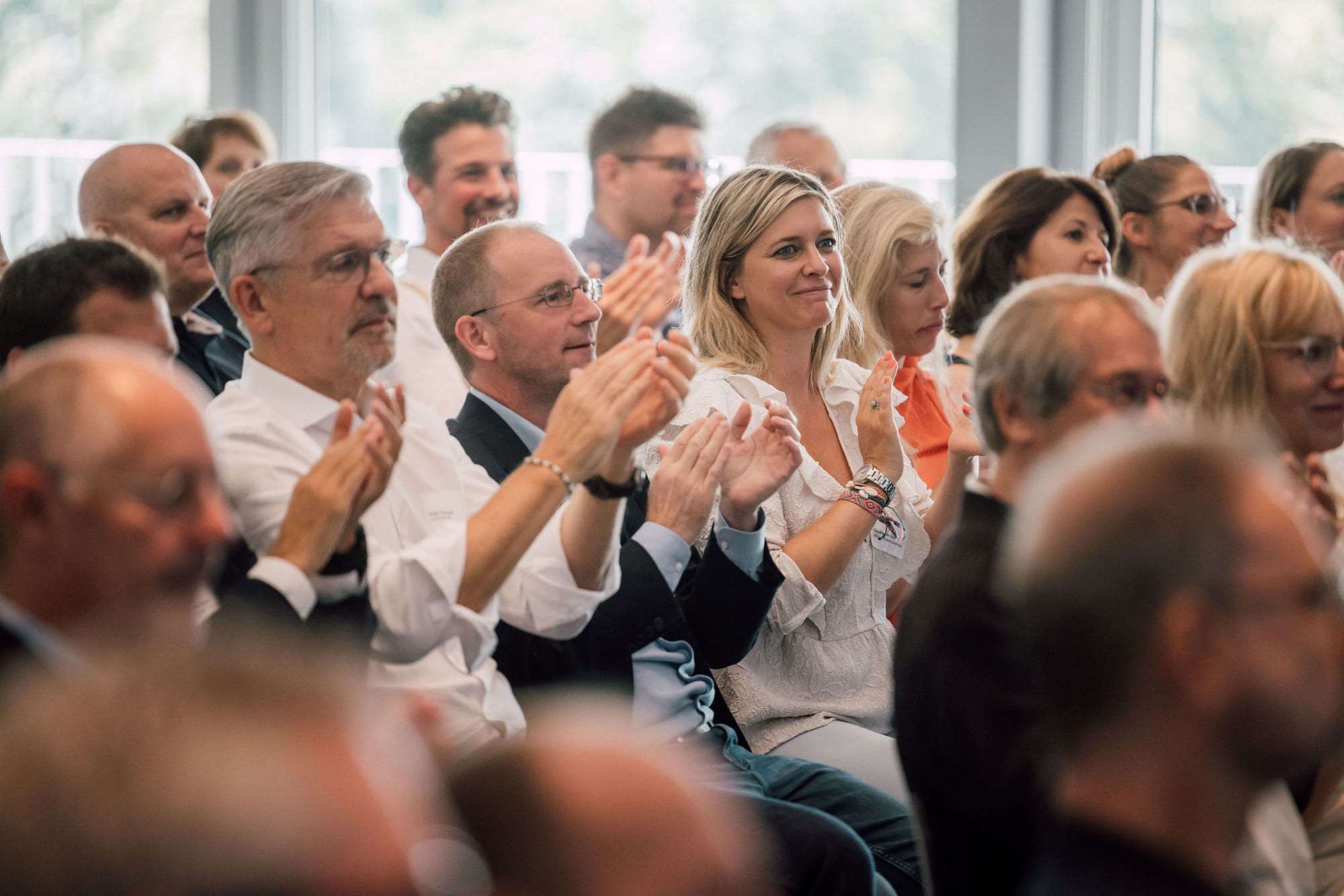 Les participants à l'AG sont assis dans le public et applaudissent
