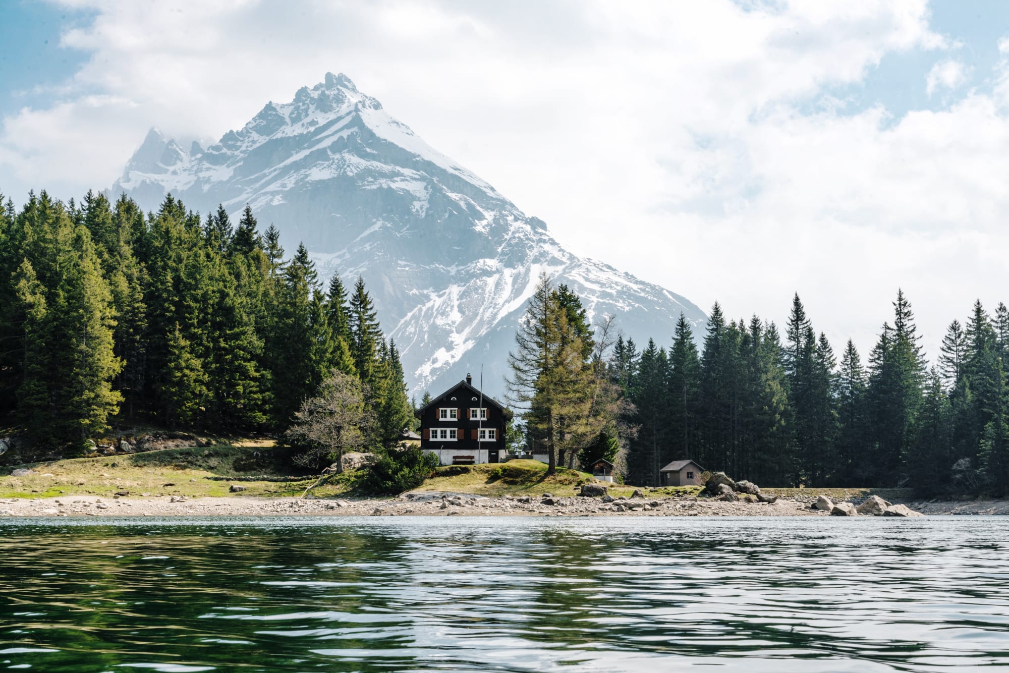 Casa sul lago con montagne e foresta sullo sfondo