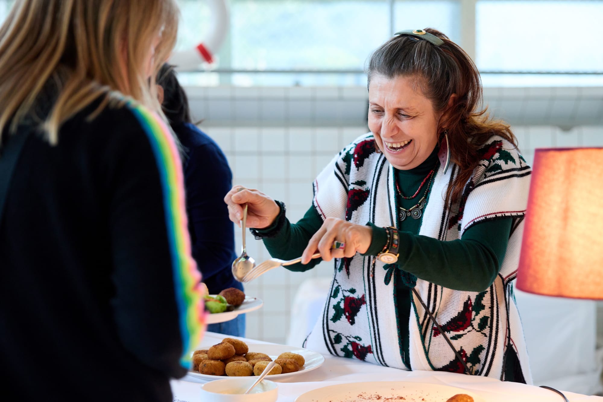 une femme souriante sert des plats au buffet