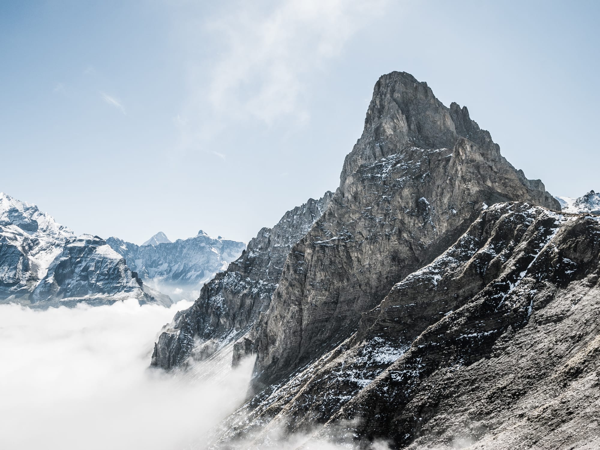 Grauer felsiger Berg Bunderspitz über dem Nebelmeer mit blauem Himmel