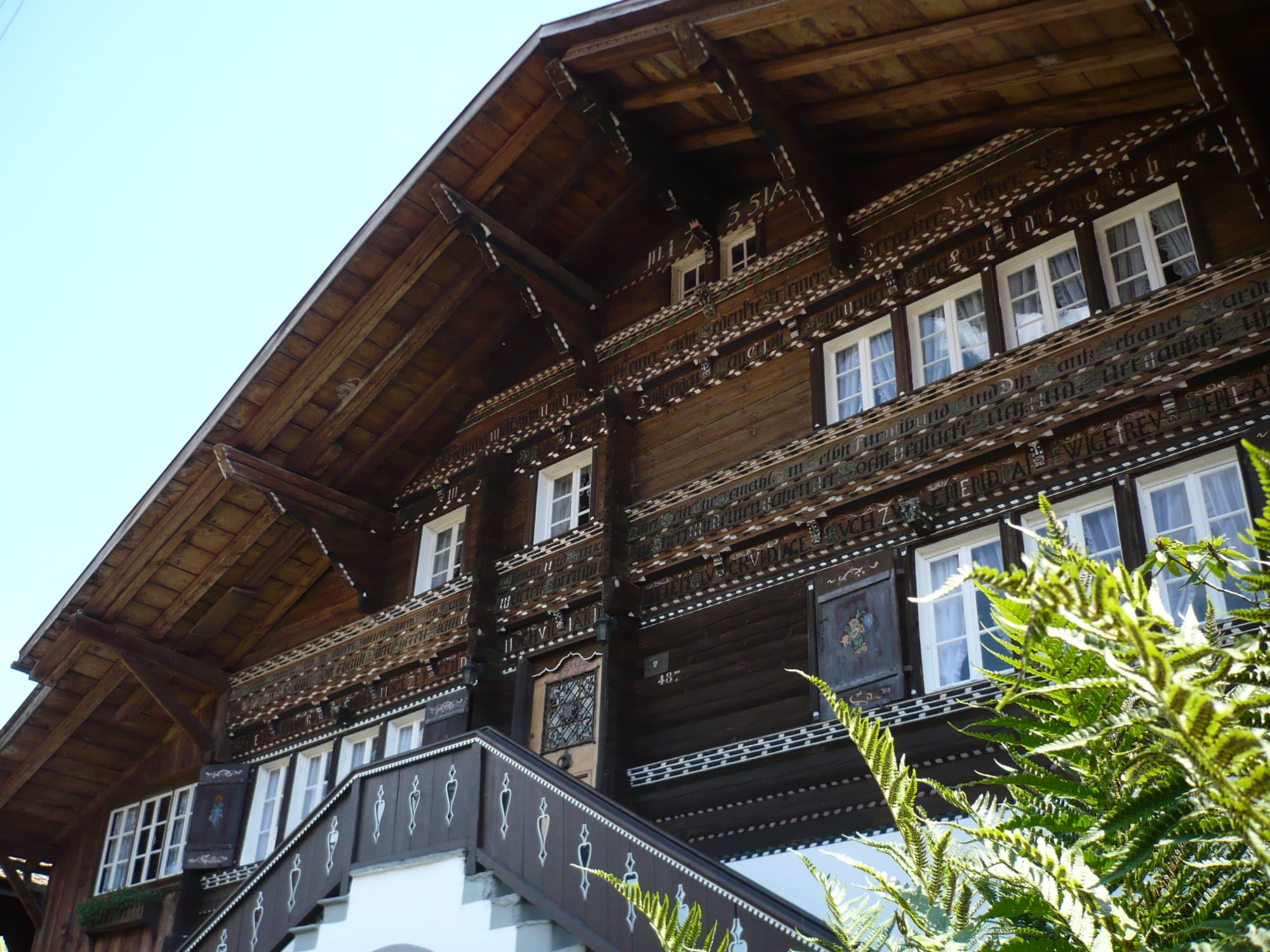 Chalet tradizionale svizzero con facciata in legno, decorazioni bianche e cornici bianche alle finestre
