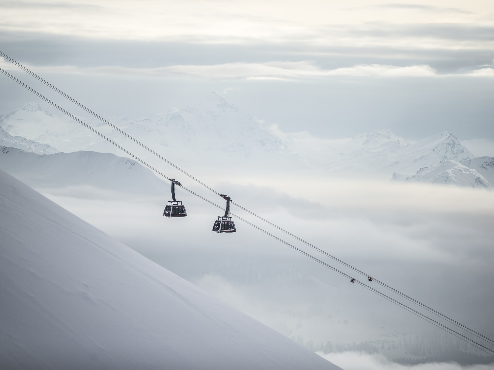 Gondelbahn vor verschneiter Bergkulisse