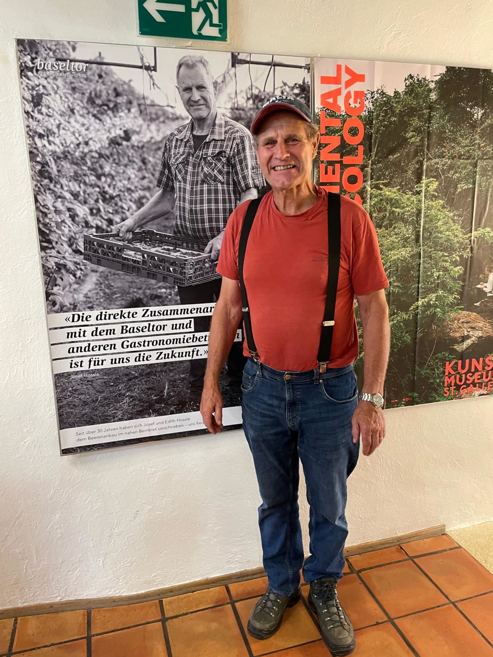 Un homme se tient devant une affiche le représentant en tant que livreur.