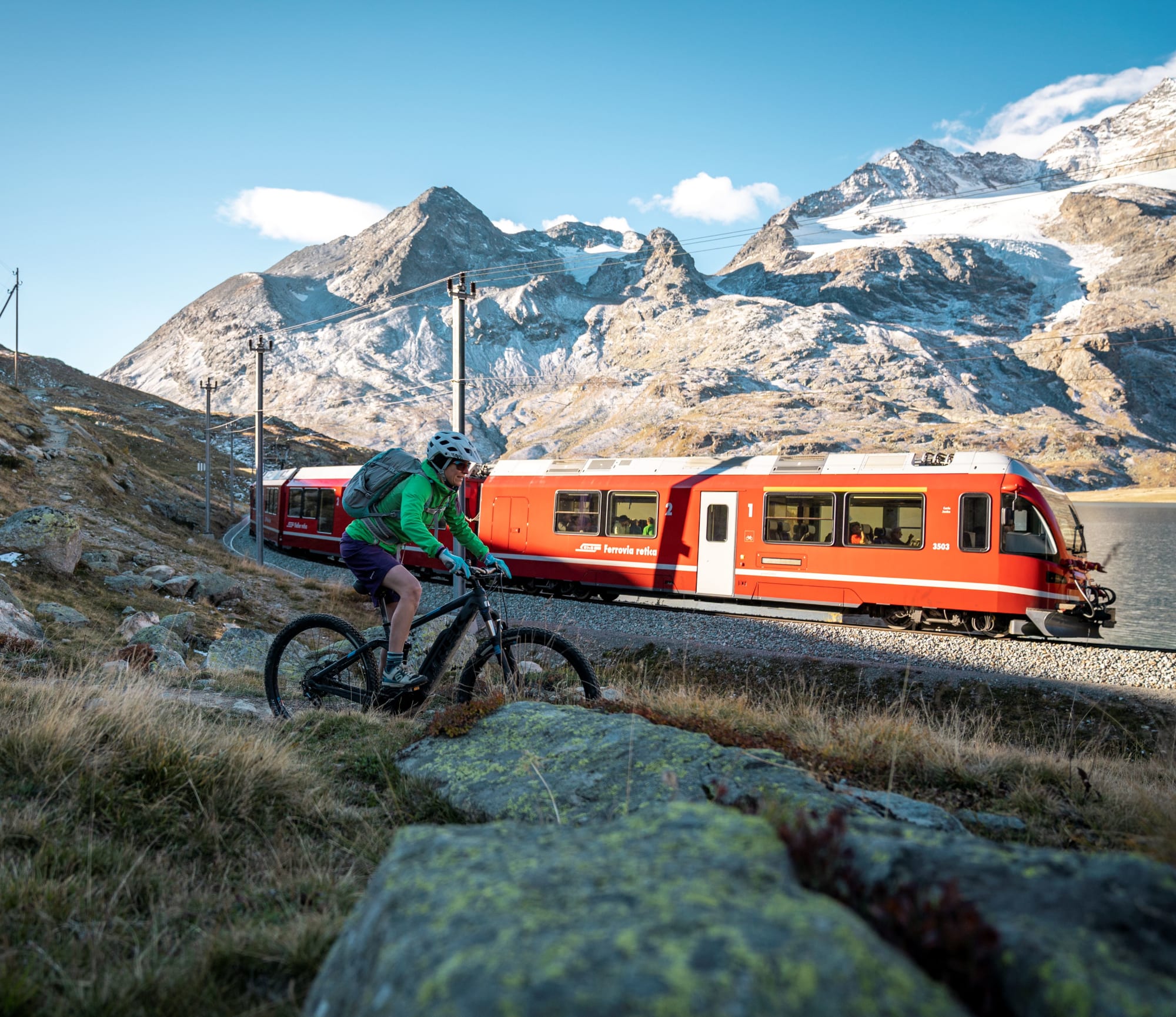 Due ciclisti davanti a un treno della RhB