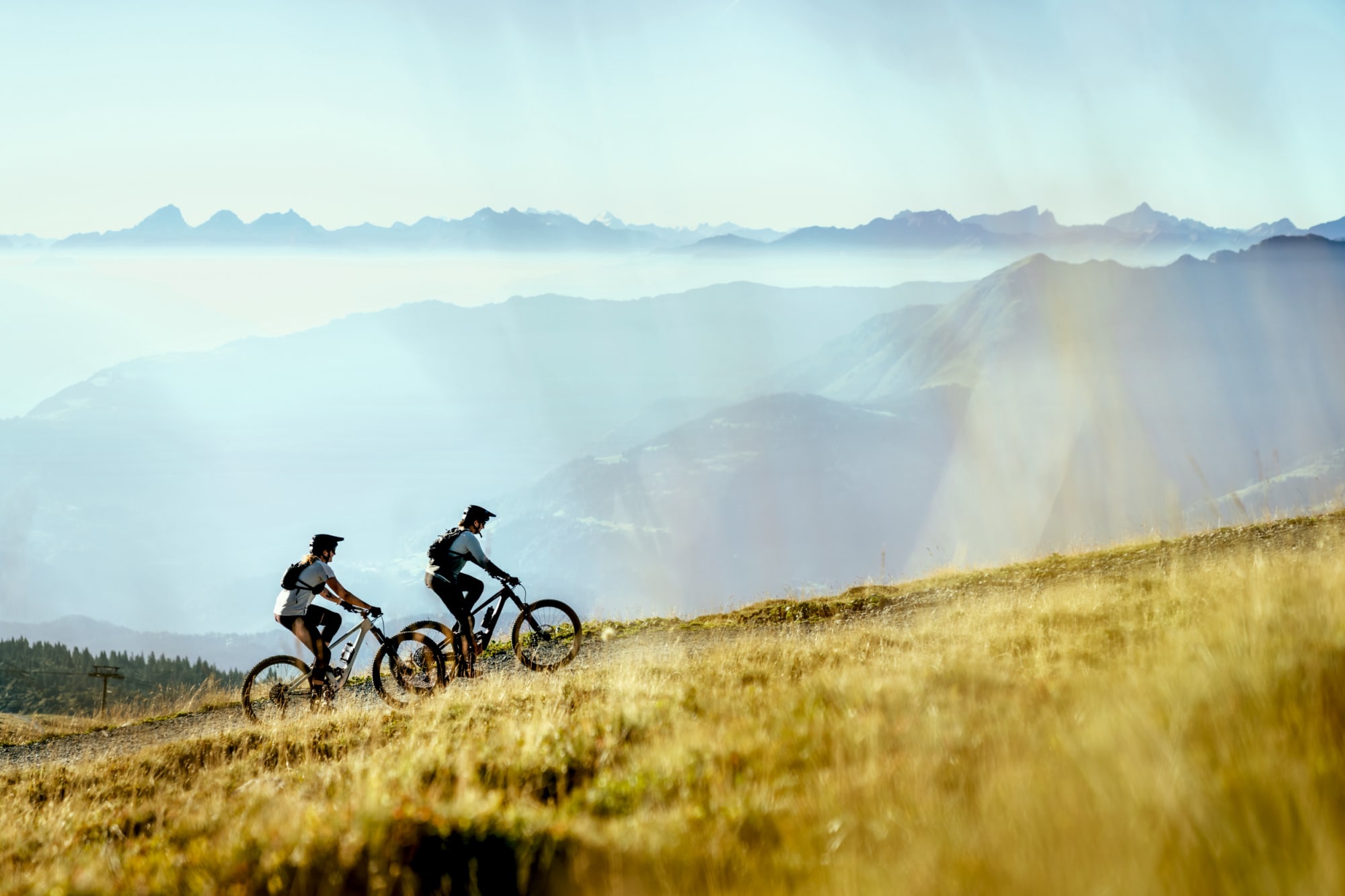 zwei Bikerinnen fahren hoch mit Bergpanorama