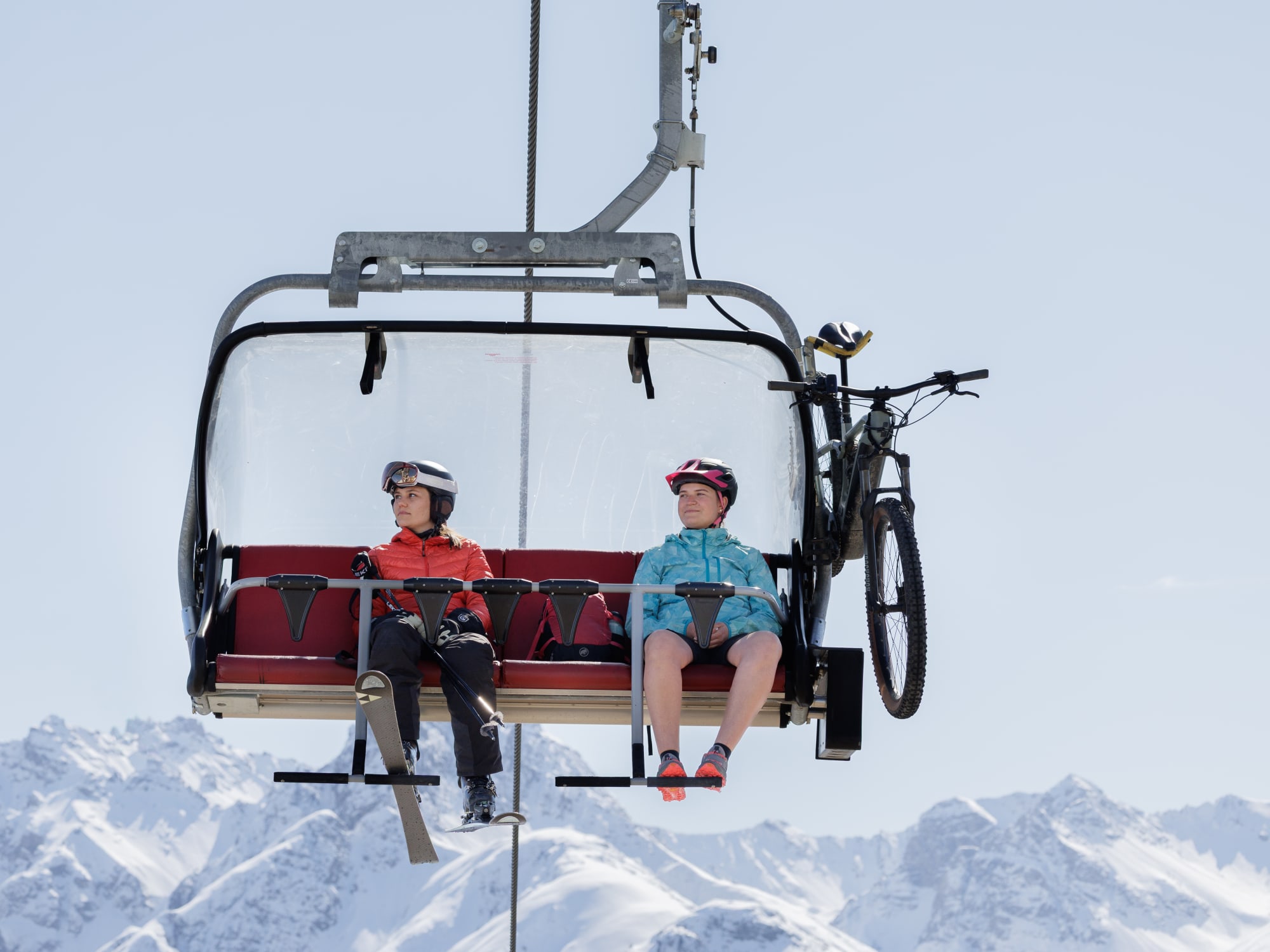 2 personnes sur un télésiège avec équipement hiver et été