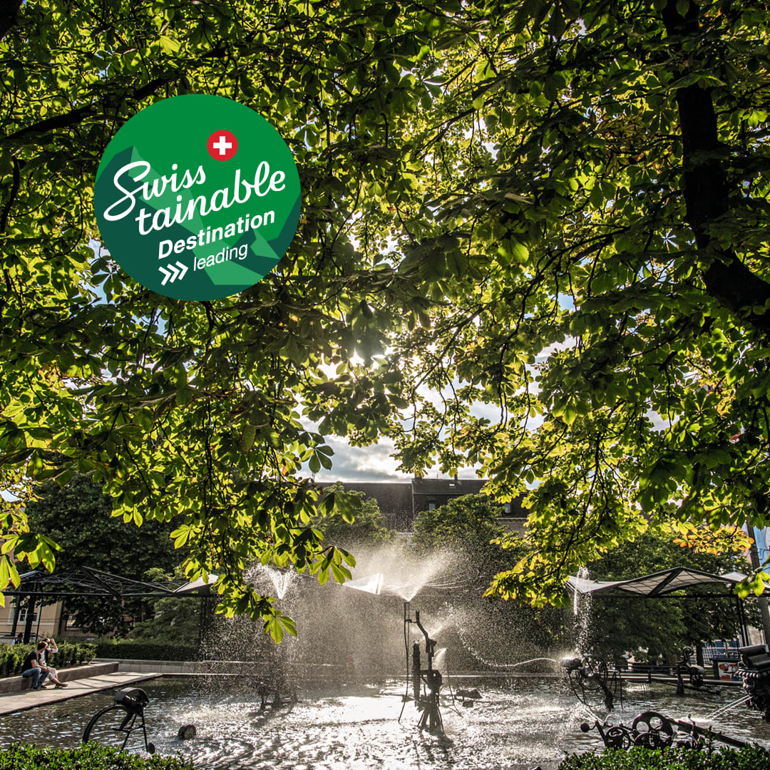 Fontana di Tinguely a Basilea Swisstainable Destination livello III – leading incorniciata da alberi