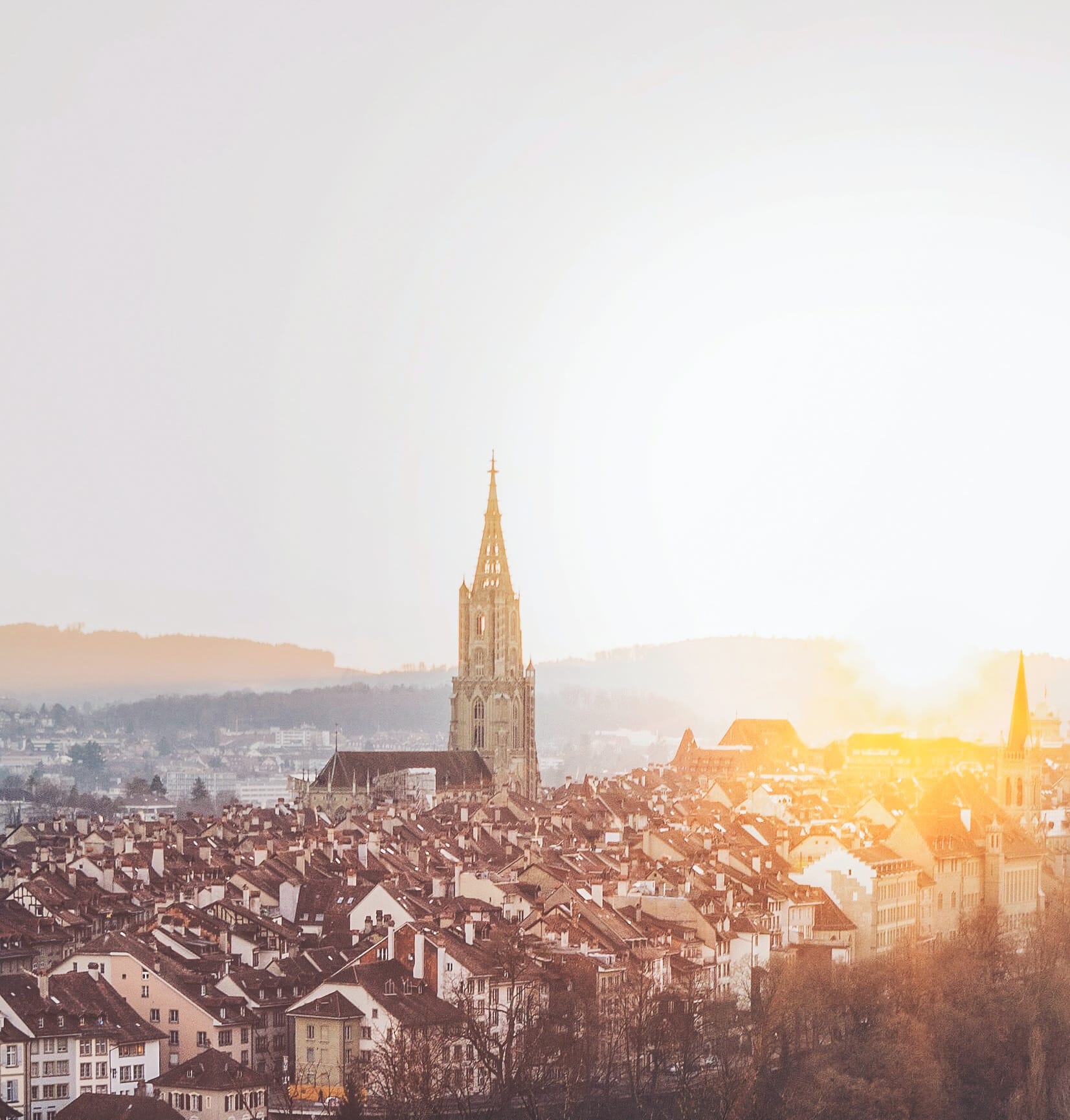 Blick auf die Berner Altstadt mit Münster, Sonnenuntergang hinter den Dächern der Altstadt.