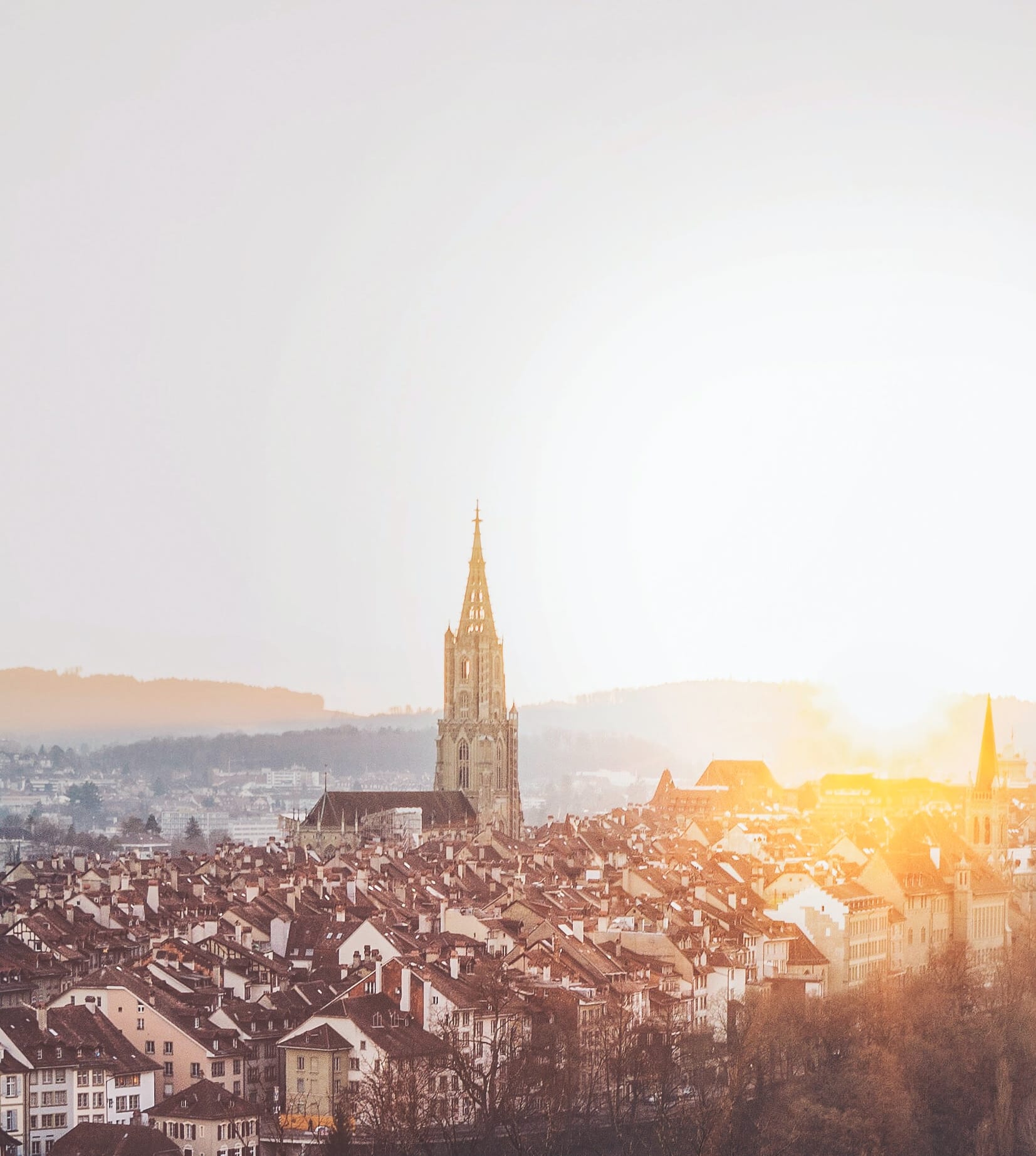 Blick auf die Berner Altstadt mit Münster, Sonnenuntergang hinter den Dächern der Altstadt.