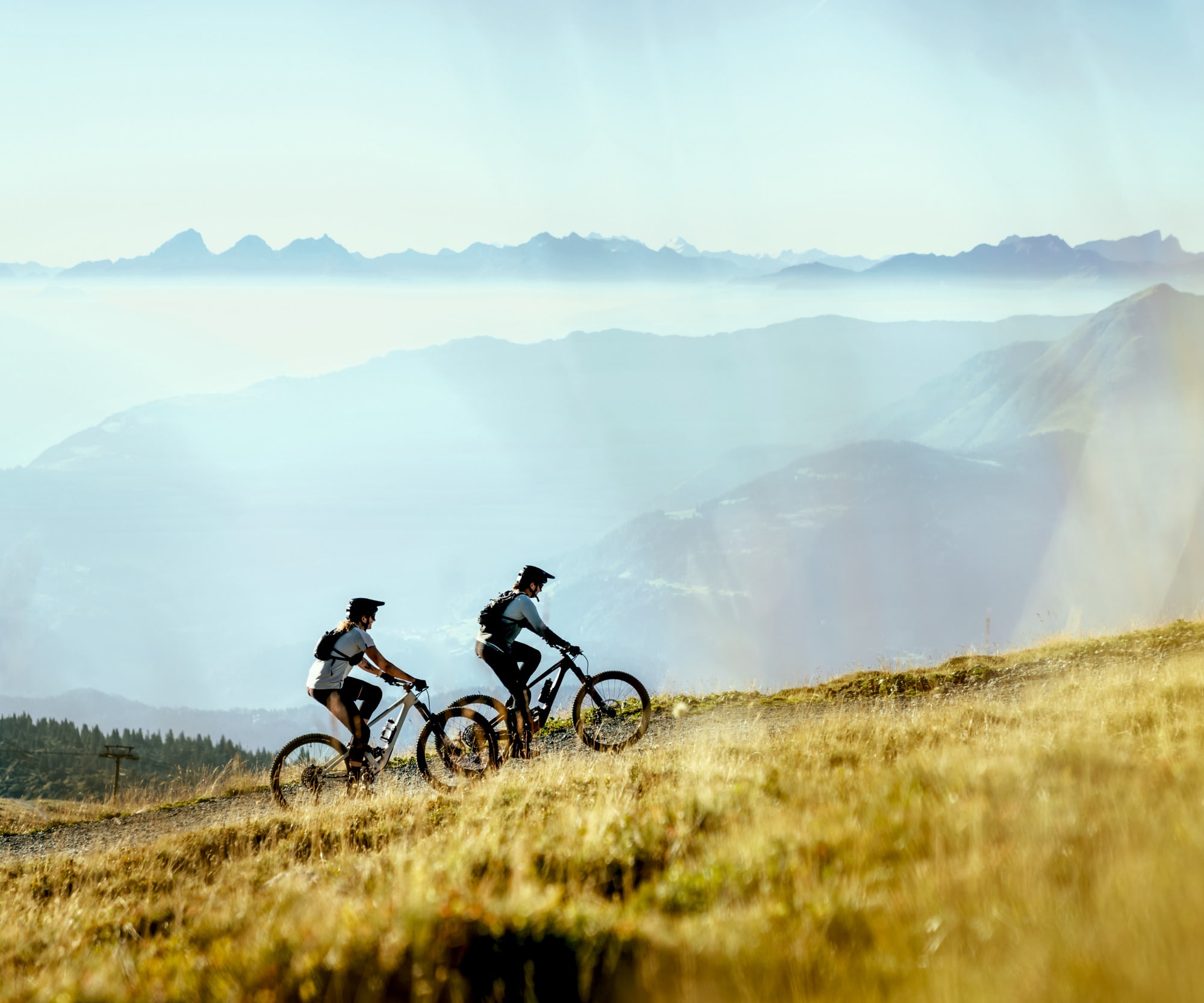 zwei Bikerinnen fahren hoch mit Bergpanorama