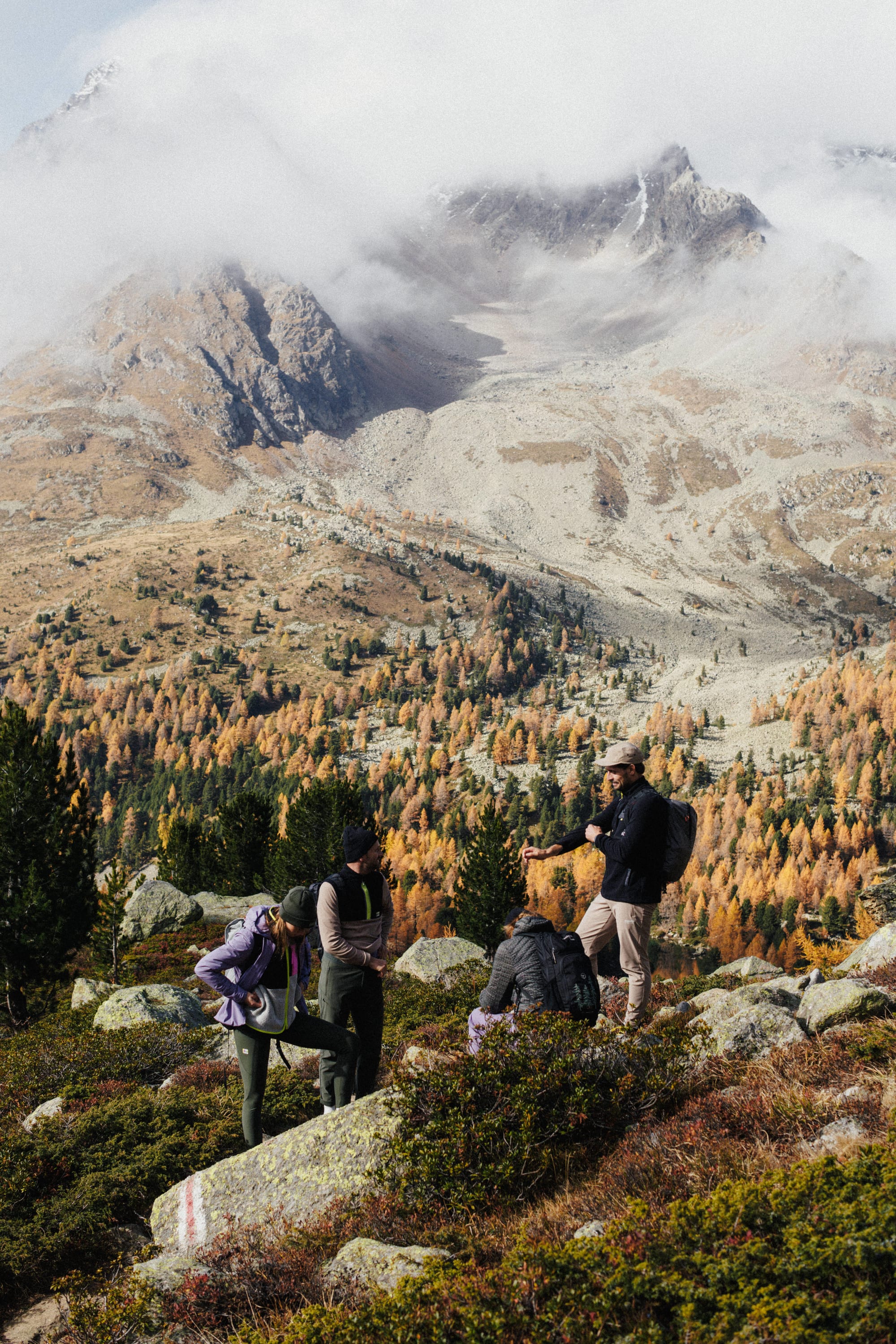 Quatre randonneurs font une pause dans un paysage automnal.