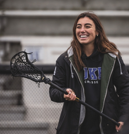 woman smiling with lacrosse stick