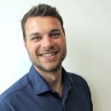 Headshot of Philipp Maucher, smiling in a navy shirt against a white wall