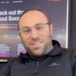Uriel Sprecher in front of a screen showing the Success.co website, the poster for his video testimonial