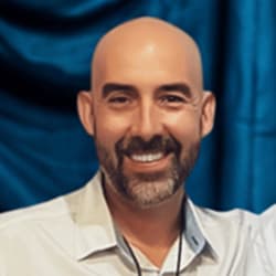 Headshot of Travis Townsend, smiling in front of a blue curtain