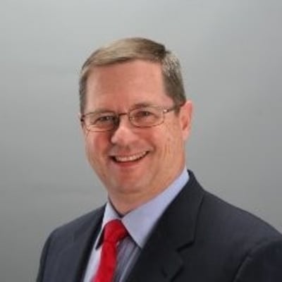 Headshot of Rip Tilden in glasses, a dark suit and red tie