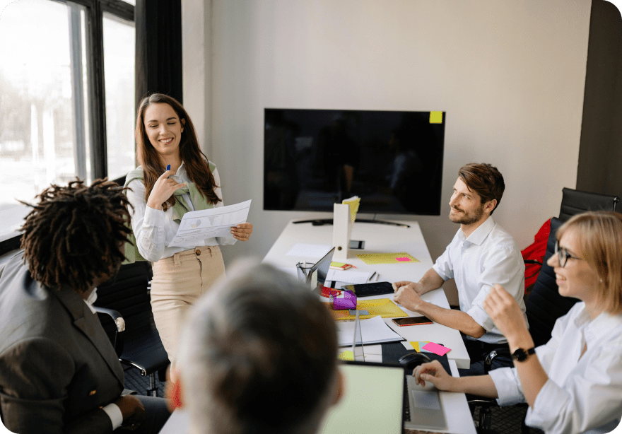 Team member presenting a printed report to smiling colleagues around a meeting room table