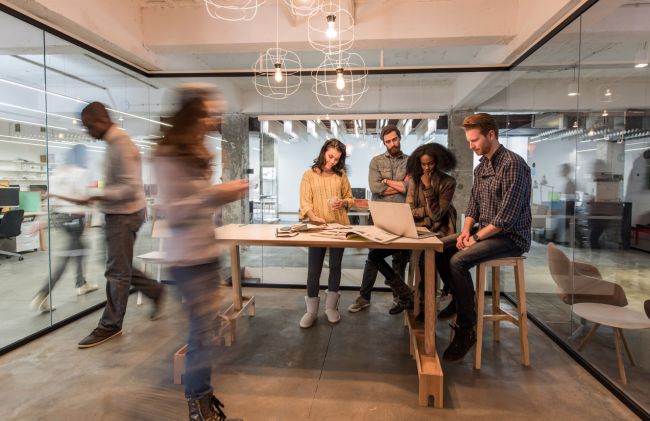 A photo of work environment with a couple of people discussing on the table