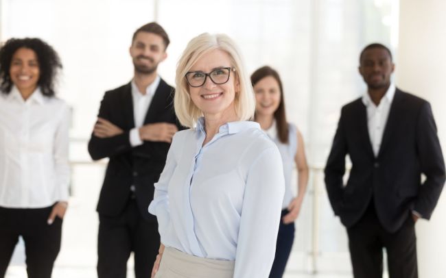 Portrait of happy older woman company ceo with diverse team