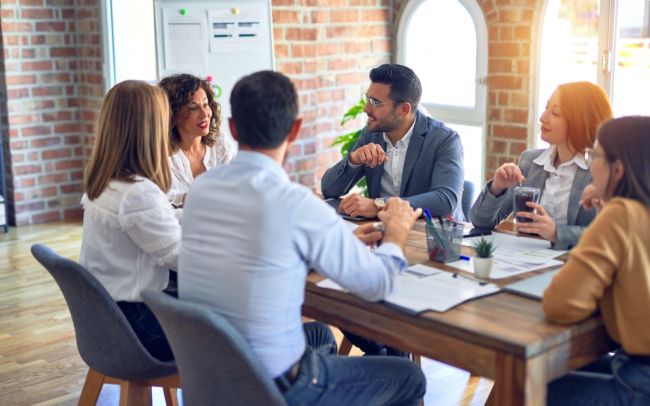 Group of business workers working together. Sitting on desk speaking at the office