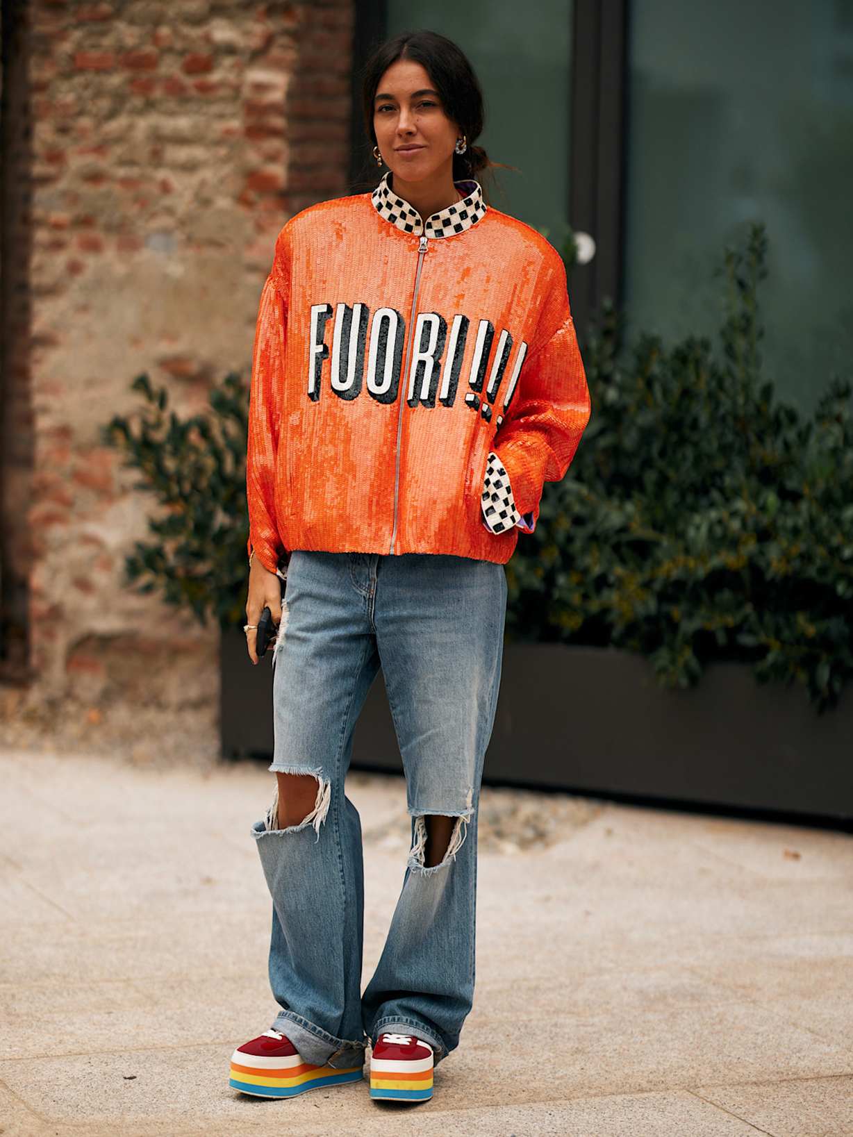 Frau mit einer grellen Lederjacke trägt den Trend bunte Plateau Sneaker dazu