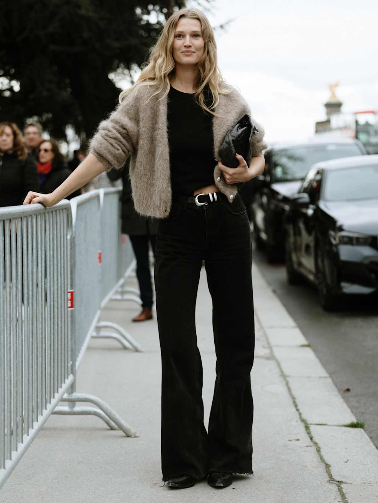 Frau trägt eine beige Strickjacke zu einer schwarzen Hose und schwarzen Boots 