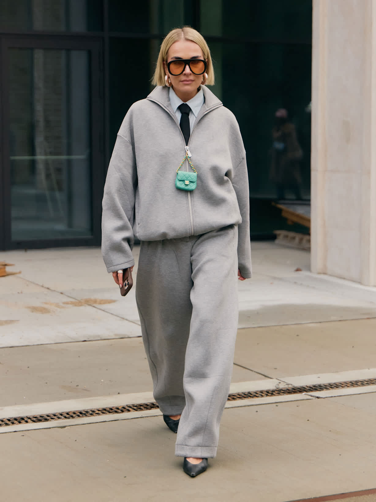 Frau trägt einen grauen Jogginganzug und eine Krawatte als trendstarken Athleisure-Style