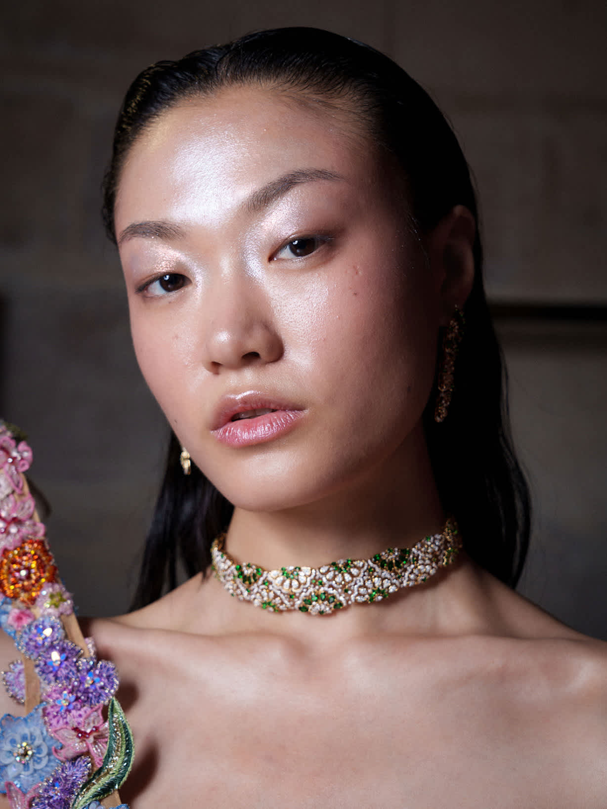 Dunkelhaarige Frau trägt Highlighter auf den Augenlidern, Wangenknochen und in der T-Zone