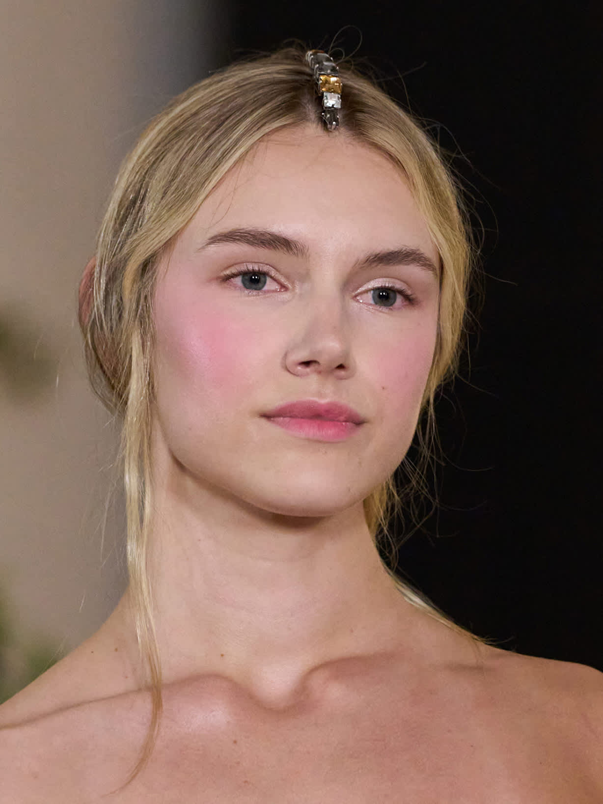 Blonde Frau trägt rosafarbenen Blush und Lippenstift