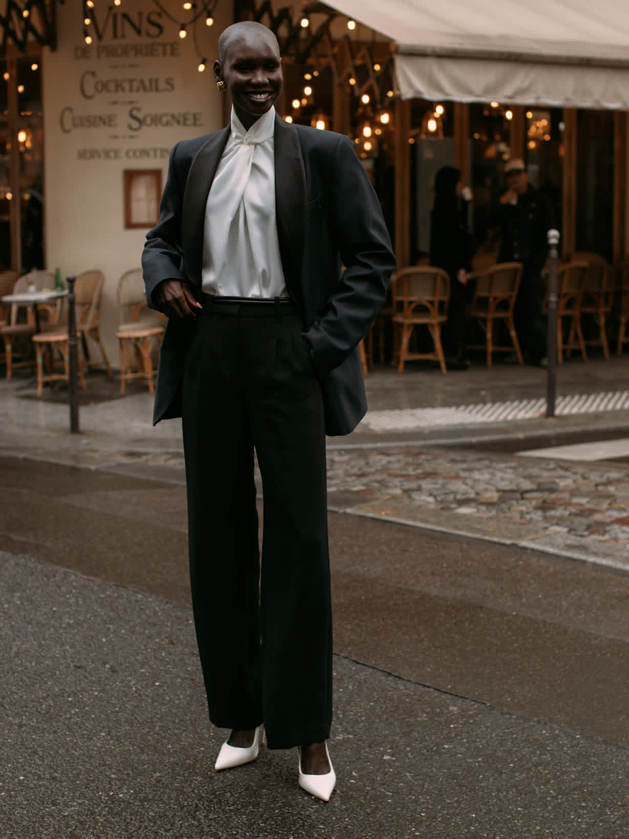 Frau trägt einen eleganten Hosenanzug mit einer hellen Seidenbluse und weißen Pumps