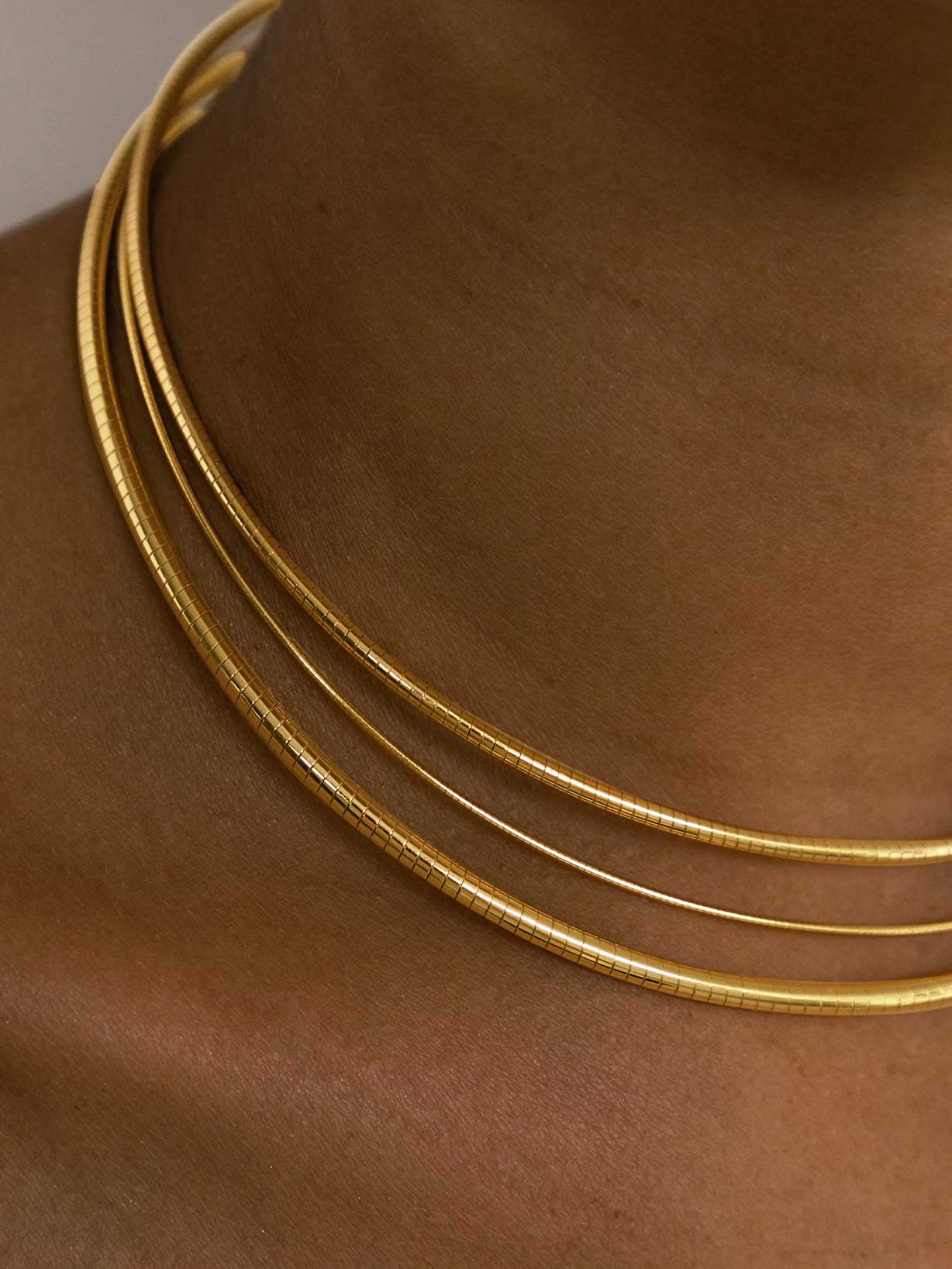 Frau trägt mehrere Ketten unt einen goldenen Choker als Trendschmuck