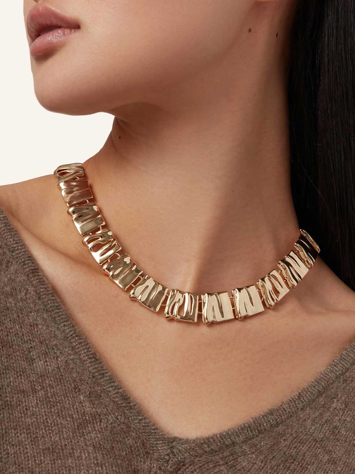 Frau trägt eine goldene Kette im angesagten Sculptural Jewelry Design