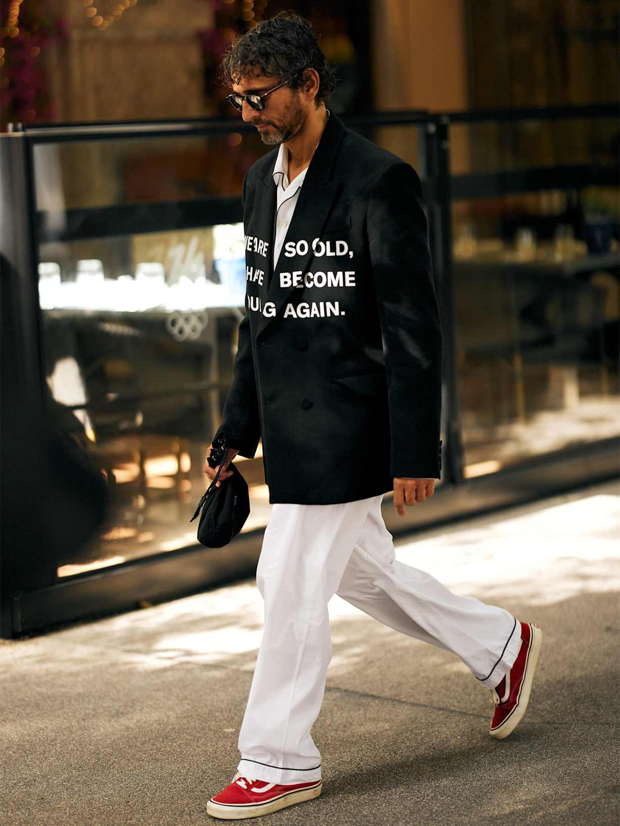 Mann kombiniert rote Vans mit weißer Stoffhose und schwarzem Sakko