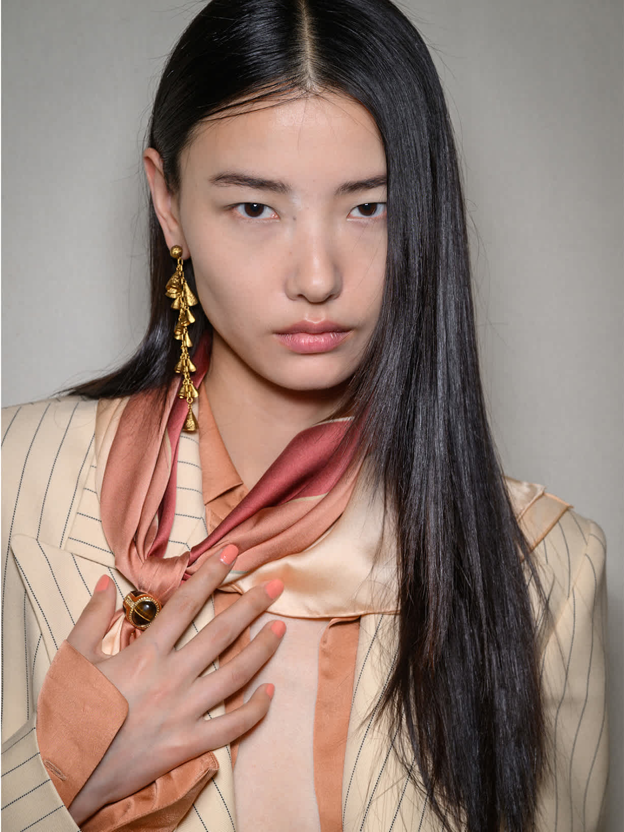 Ciemnowłosa kobieta prezentuje lakier w modnym kolorze brzoskwiniowym