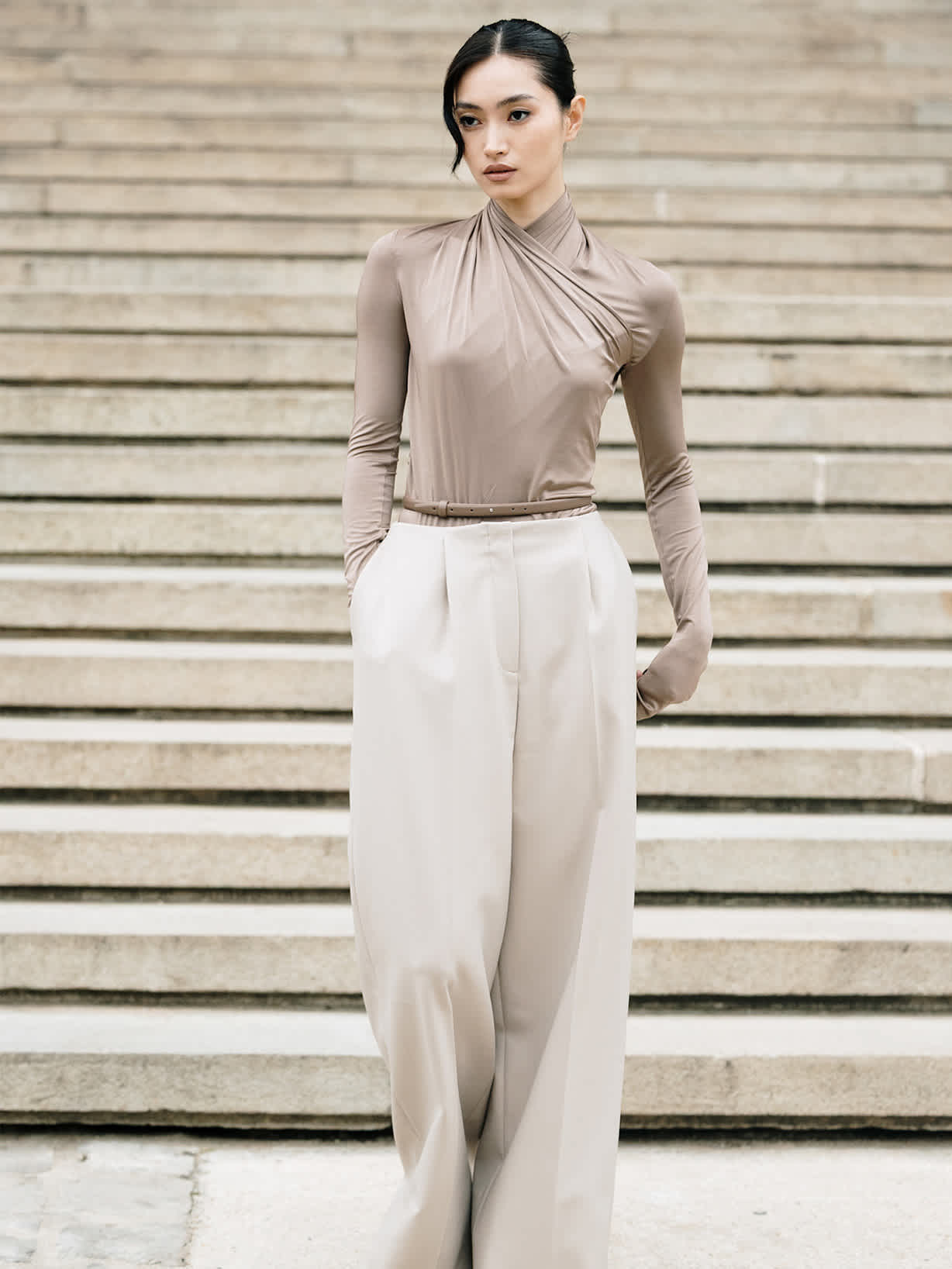 Dunkelhaarige Frau kombiniert beige Hose mit elegantem Wickeloberteil