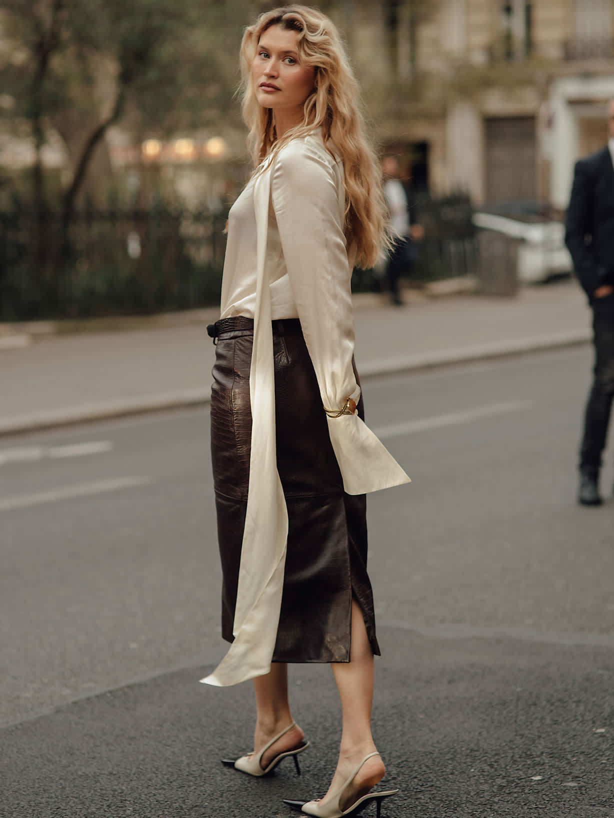 Herbstliches Damen-Outfit mit cremefarbener Satinbluse, braunem Lederrock in Midilänge und eleganten Slingback-Pumps im Streetstyle.