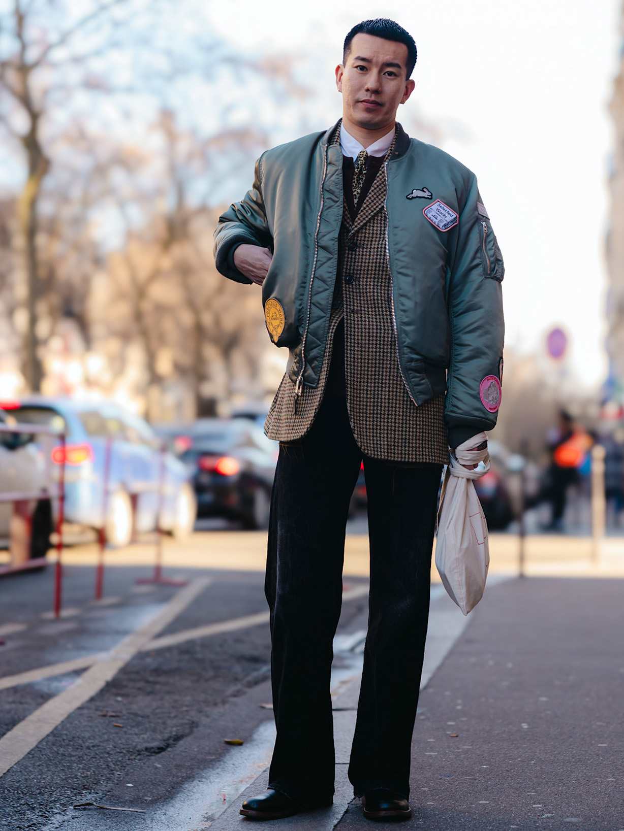 Mann trägt eine grüne Jacke zu einer schwarzen, weiten Hose und dazu Leder-Boots, ein Streetstyle-Look aus Modetrends im Herbst.