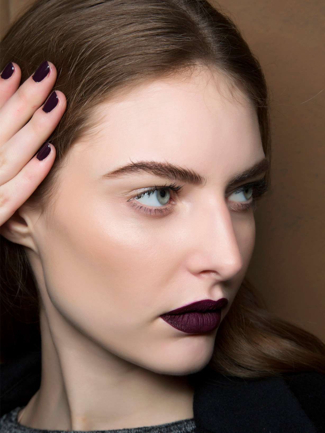 Brünette Frau trägt Plum Nails mit dazu passendem Lippenstift